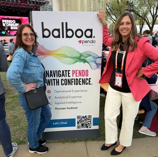 Two Balboa teammates standing beside a Balboa and Pendo certified partner banner