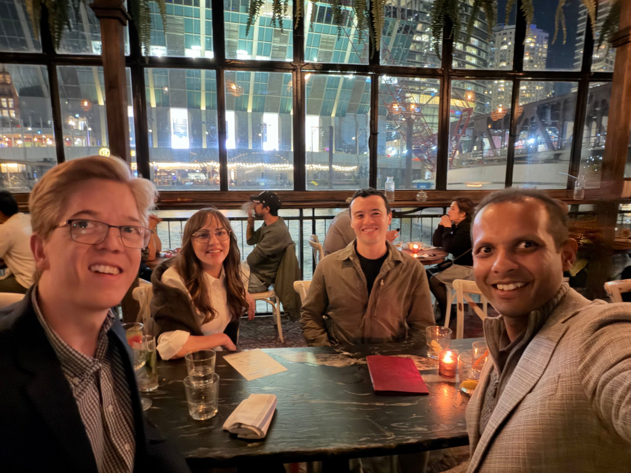 Balboa team members and partners at dinner in a restaurant overlooking a river at night